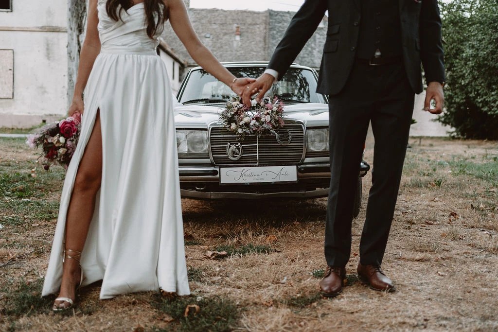 Romantična fotografija mladenca ispred starog automobila u boji.