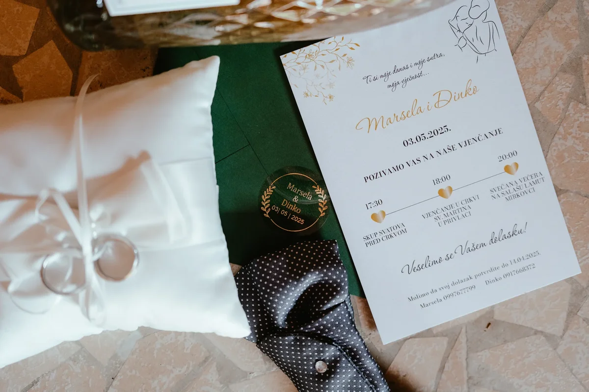 Profesionalna fotografija detalja vjenčanja u Našicama – pozivnica, muška kravata i burme za mladence Marselu i Dinka.