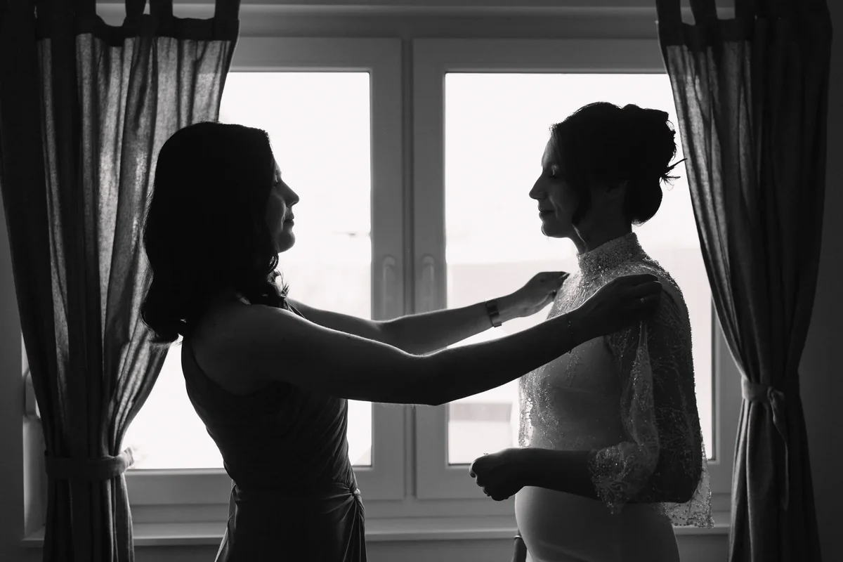 Emotivna fotografija vjenčanja u Našicama – kuma popravlja vjenčanicu mladenki Marseli netom prije ispraćaja.