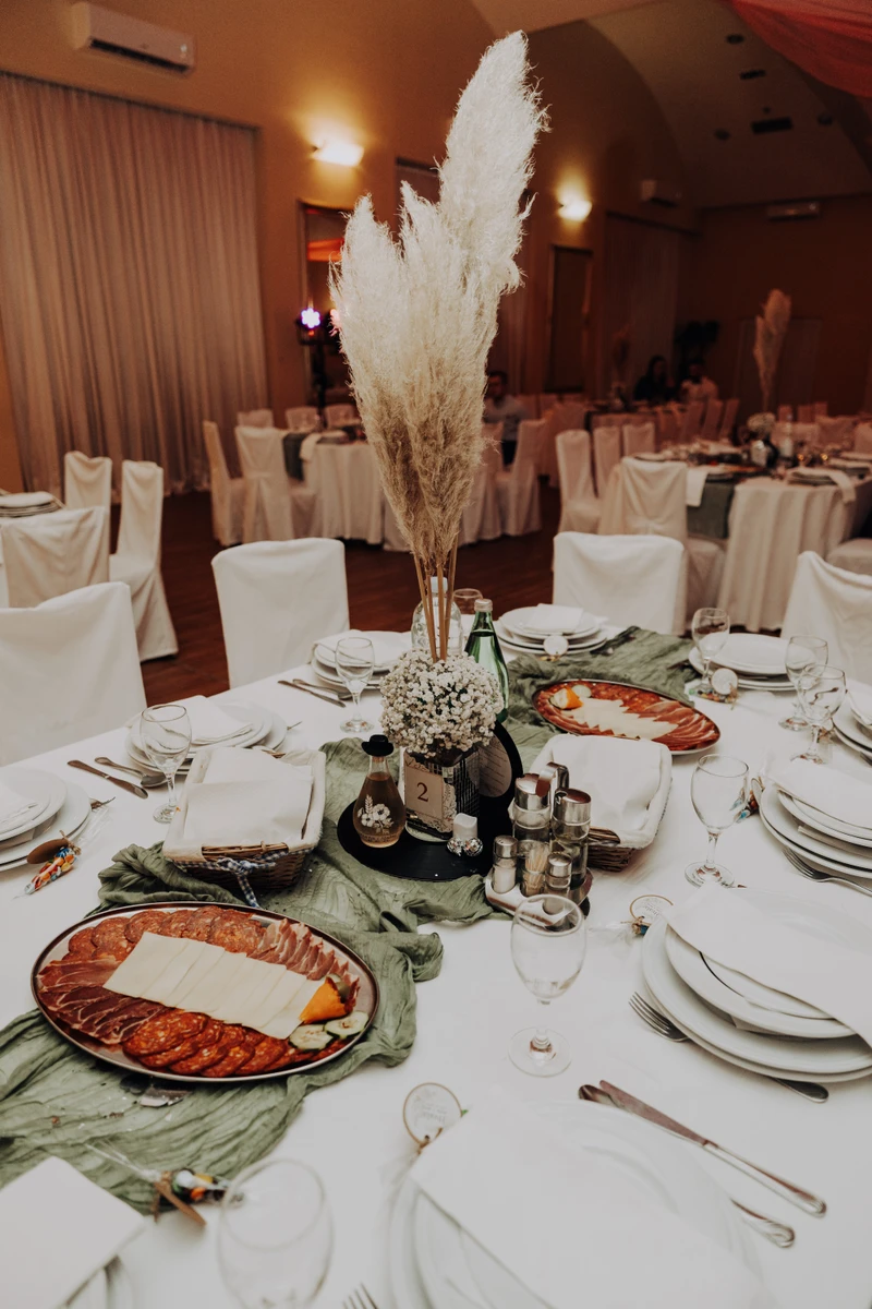 Elegantno dekoriran stol za goste na vjenčanju s cvjetnim aranžmanima i svijećama.