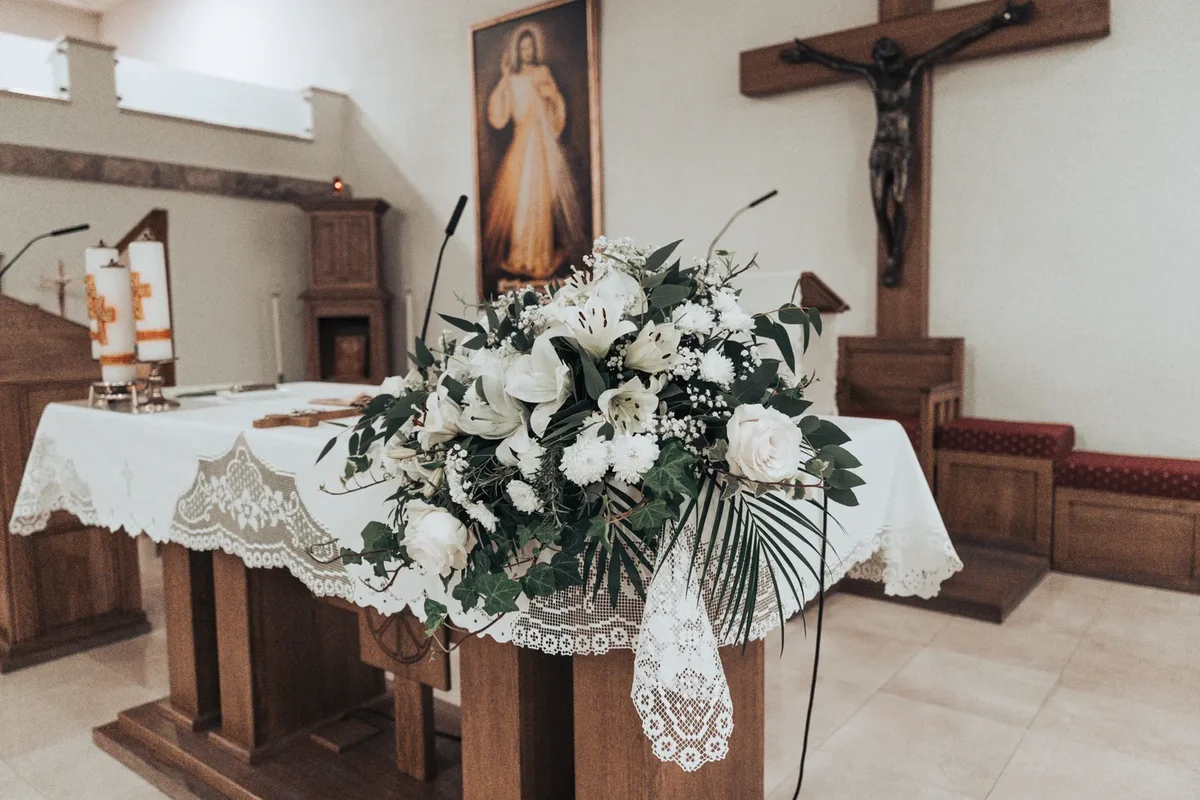 Crkveni oltar s bijelim cvjetnim aranžmanom pripremljen za vjenčanje.